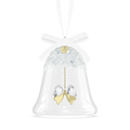 A clear glass bell-shaped Christmas ornament with a white ribbon bow at the top, a glittery white top section, and a dangling gold-tone heart-shaped ornament with two clear faceted crystal pendants.