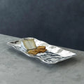 Silver wavy plate with crackers and cheese on a gray surface and dark background