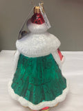 Decorative ornament with green skirt and red ball on a plain background