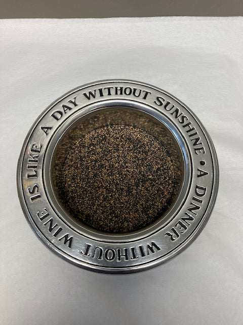 Decorative metal plate with text and dark brown center on a white background