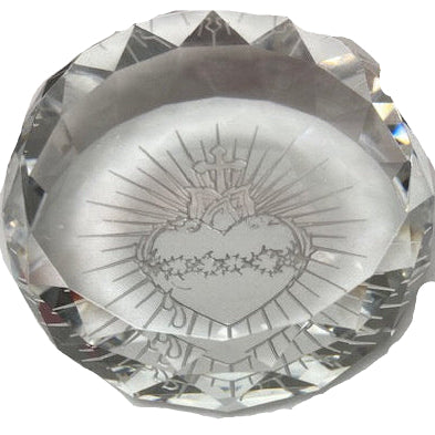 A clear faceted crystal paperweight featuring an engraved Sacred Heart of Jesus design in the center, shown on a plain white background.